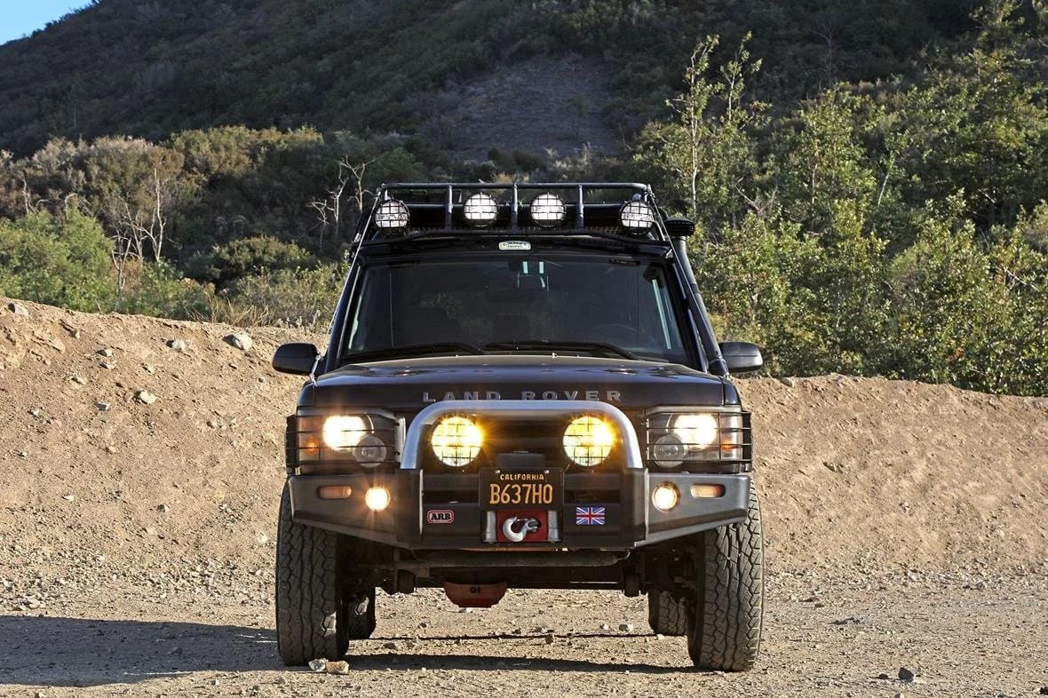 Black Land Rover Discovery II with auxiliary lights on a dirt trail
