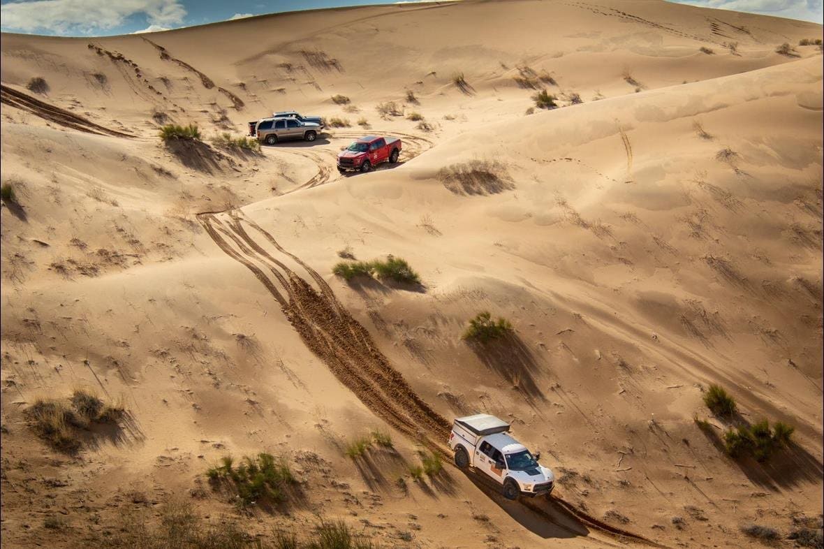 Ford F-150 Raptors crossing a large sand dune in Mexico